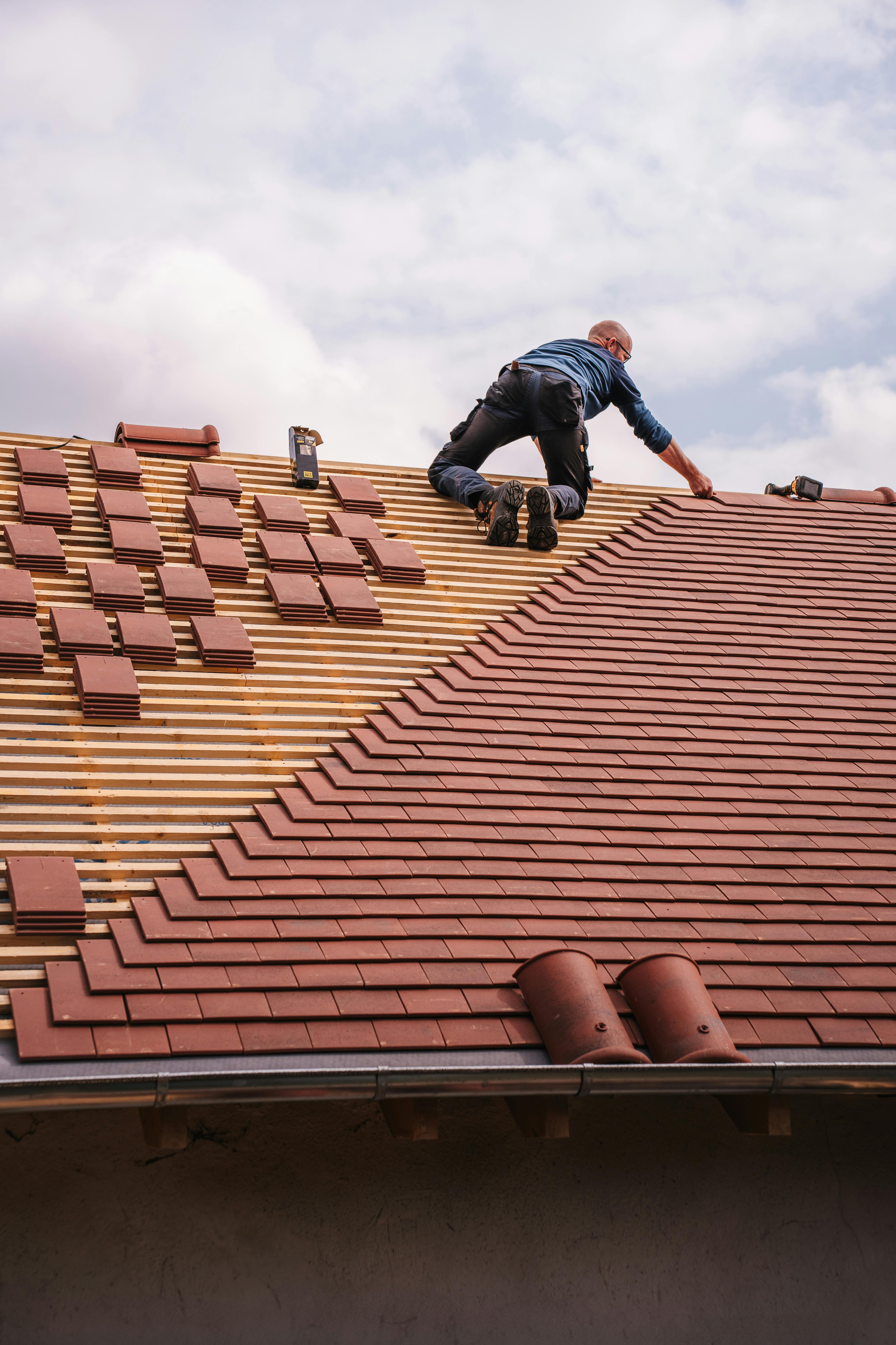 Dakdekker bezig met reparatie van dakpannen